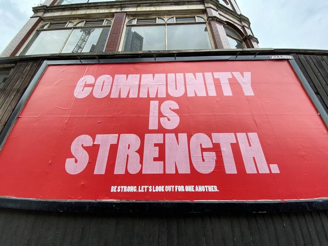 Red sign with white letters that says Community is Strength.