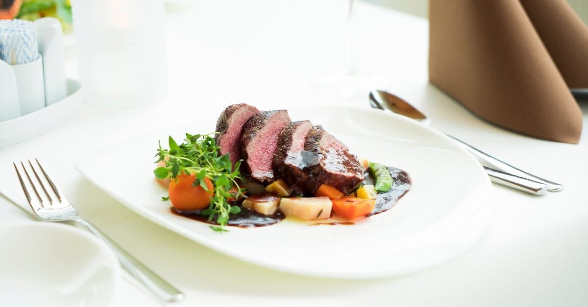 a cooked steak and side salad on a white plate resting on a white tablecloth