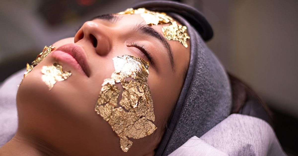 A woman with gold leaf foil on her face during a spa treatment.