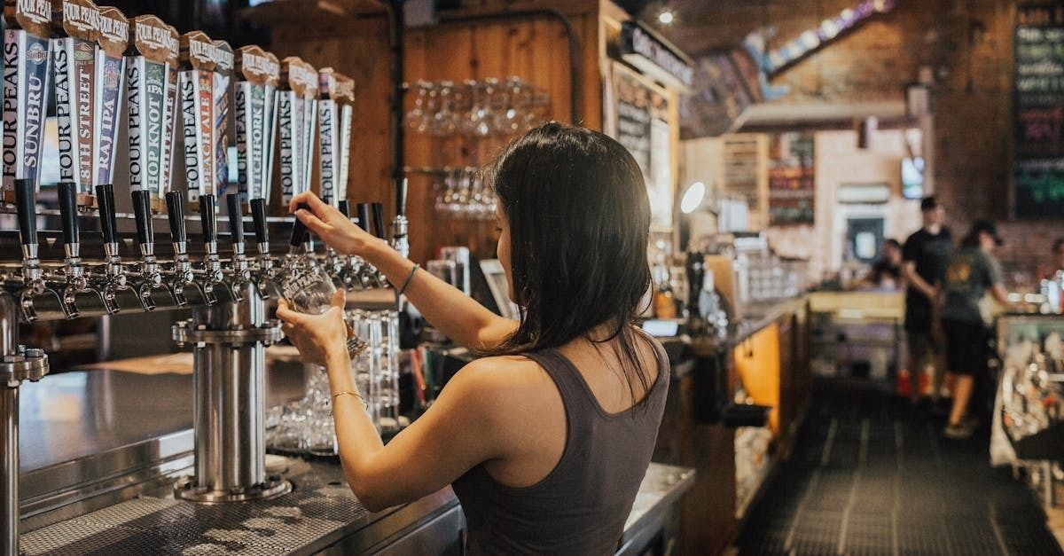 Bartender pouring a draft beer at a bar lined with tap handles