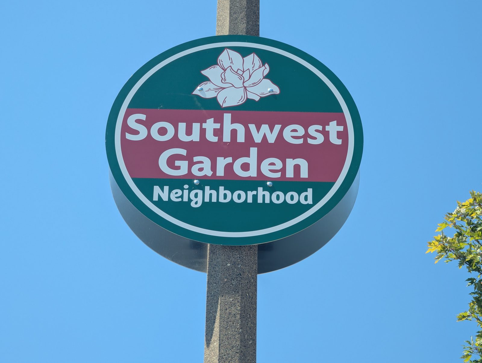The round green and maroon Southwest Garden Neighborhood sign in St. Louis, with a magnolia blossom above the name