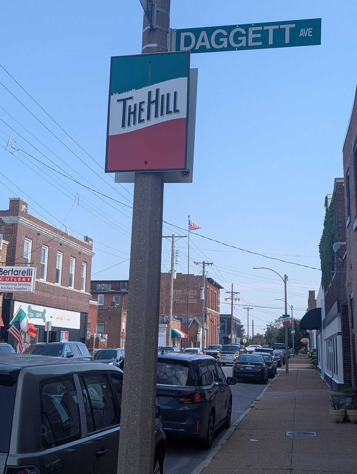 The green, white and red The Hill neighborhood marker under the Daggett Avenue street sign in St. Louis