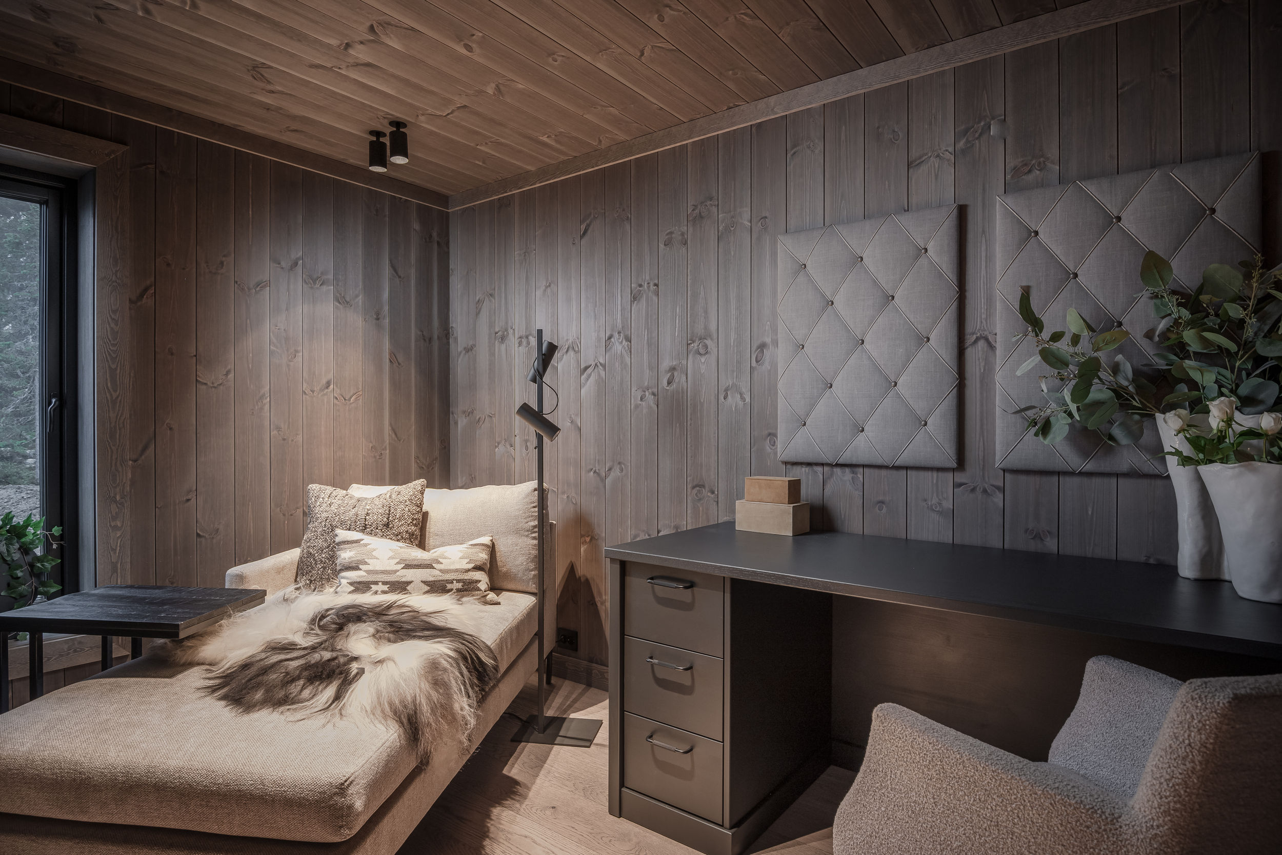 Hjemmekontor i hytte med skrivebord, skuffeseksjon og daybed ved vinduet.