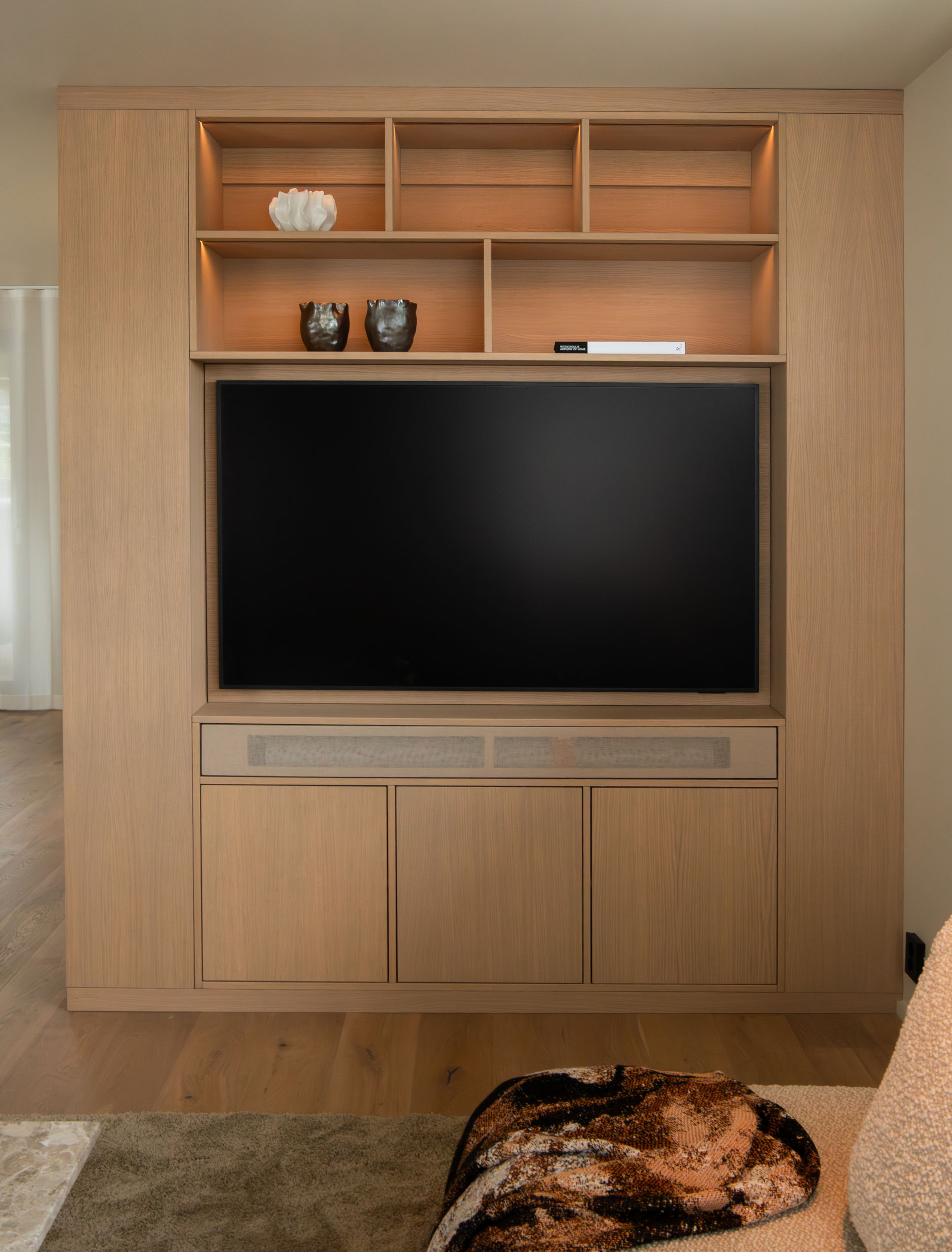 Plassbygget medievegg i eik med innfelt TV, belyste hyller og skjult oppbevaring.