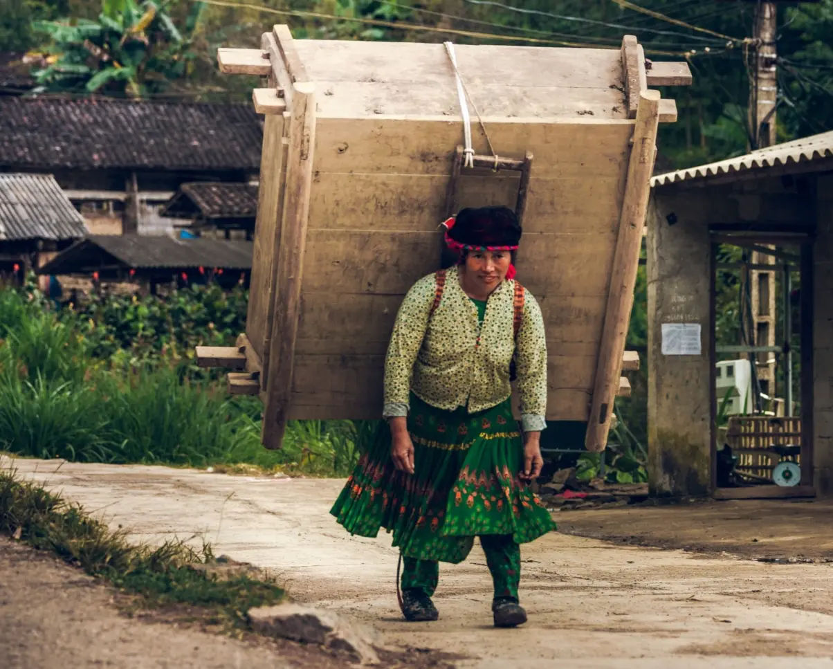 local ethnic women carry a heavy item on her back - solo ride ha giang motorbike experience adventure