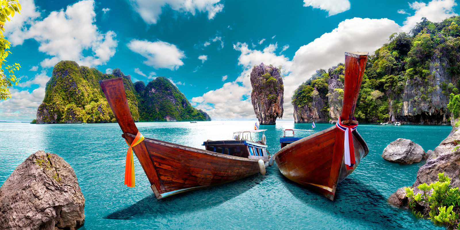 Long tailed boat Ruea Hang Yao on beautiful deep blue sea and blue sky in front of island background in Phuket Thailand