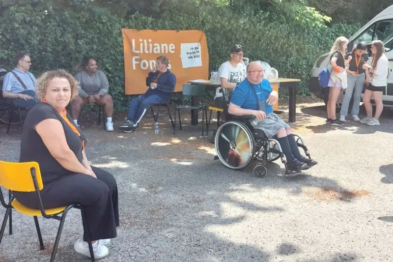 Deelnemers van De Koninklijke Loop ontspannen bij een stand van Liliane Fonds in Apeldoorn, inclusief rolstoelgebruiker