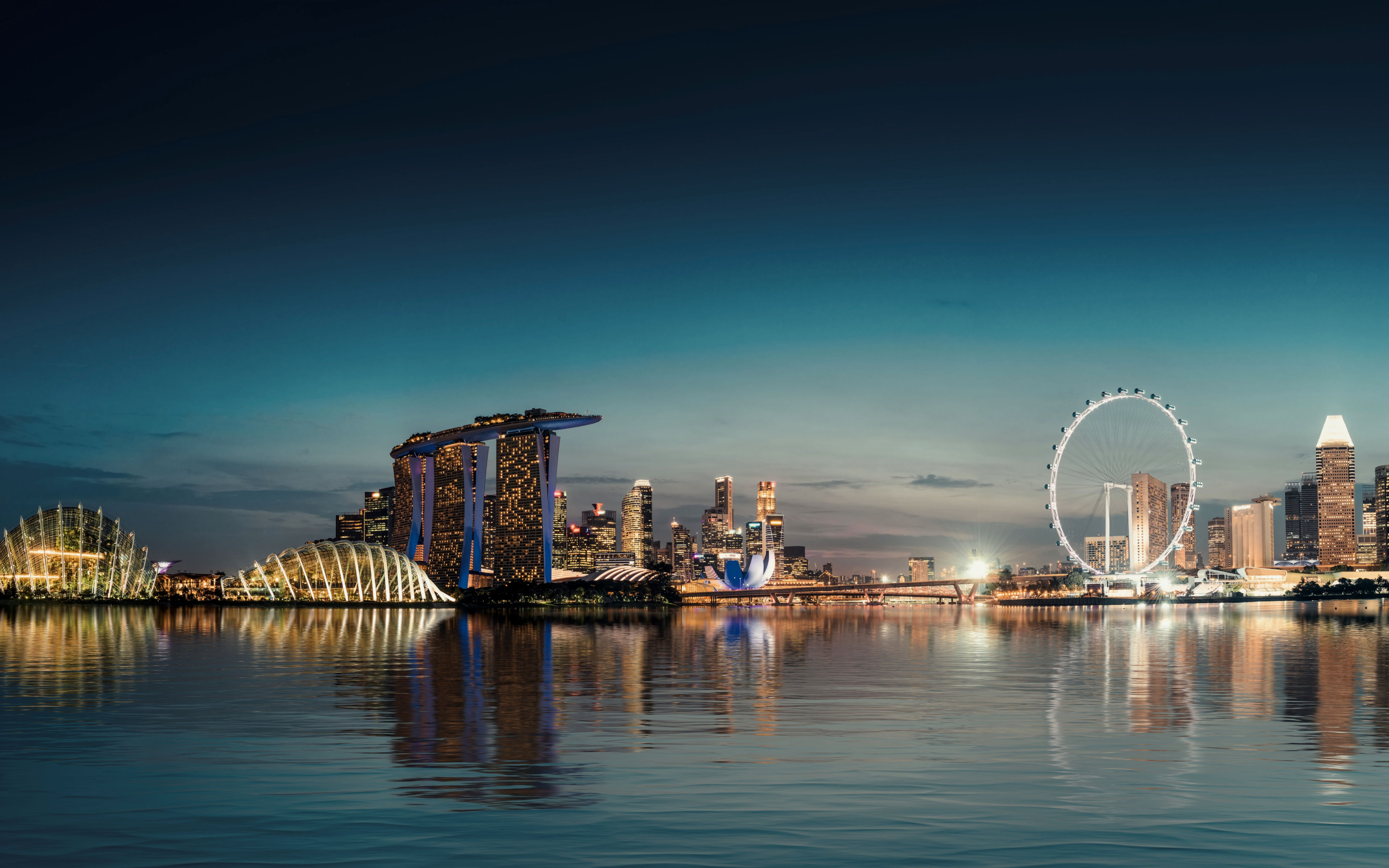 Futuristic modern architectural structures of Marina Bay Sands skyline illuminated during sunset in Singapore
