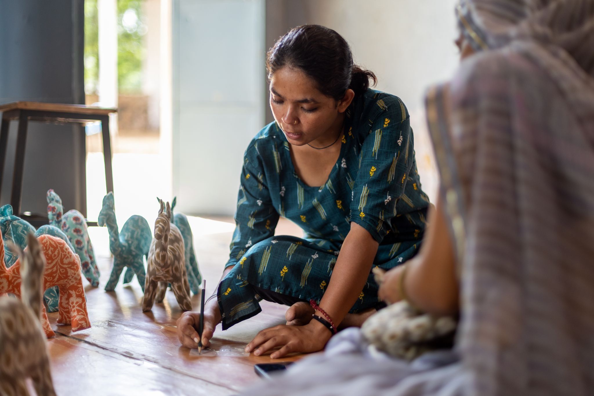 A woman artisan's hands making a small cloth toy in natural light.