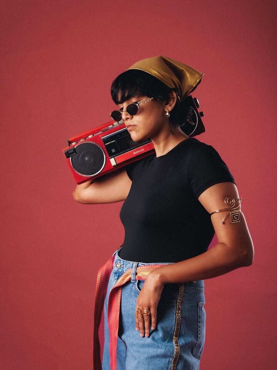 Siri Xander holding a red boombox against a red backdrop.