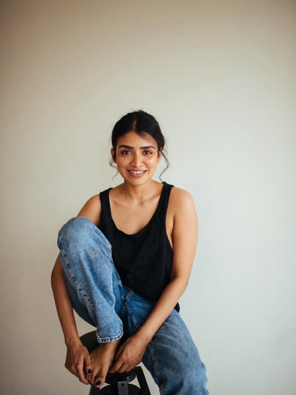 Monisha Mohan seated and smiling against a light backdrop.