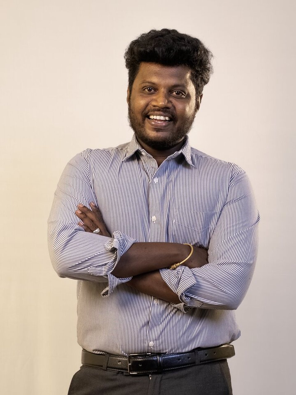 Pradeep standing with folded arms and smiling.