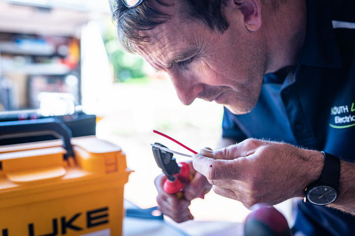 Electrician using a multimeter to trace an intermittent electrical fault in a Waldport property