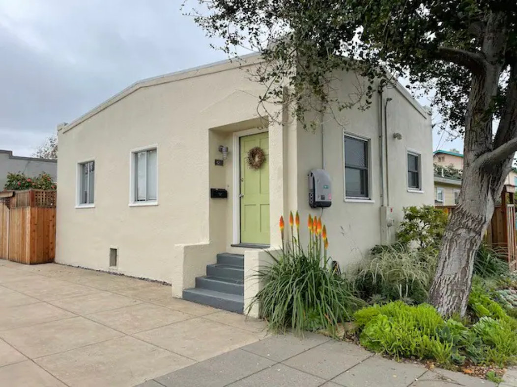 Charming stucco bungalow with inviting entry, driveway, and lush curb appeal – Main image