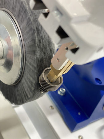 A cluster gear contacts the 320-grit Scotch-Brite embedded nylon wheel.