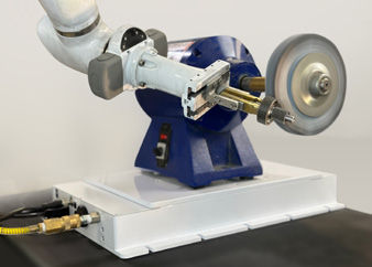 The pneumatically controlled deburring platform sits beneath the blue motor housing.