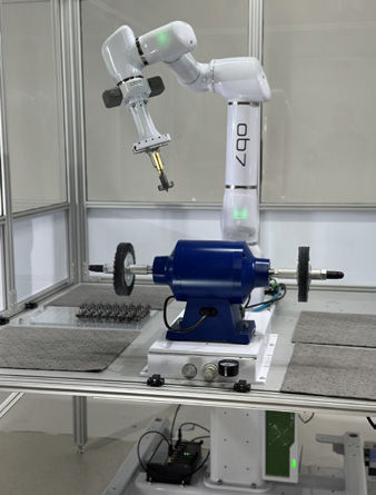 Inside the enclosed cell, the OB7 holds a part between dual deburring wheels. The offset and pressure adjustment dials are visible on the platform base.