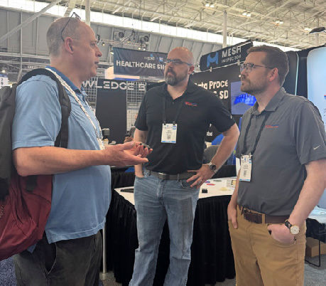 Metallurgist Art Reardon (left) discusses printed gears in Filmatrix's booth with Ryan Besch (middle) and Logan Pensinger (right).