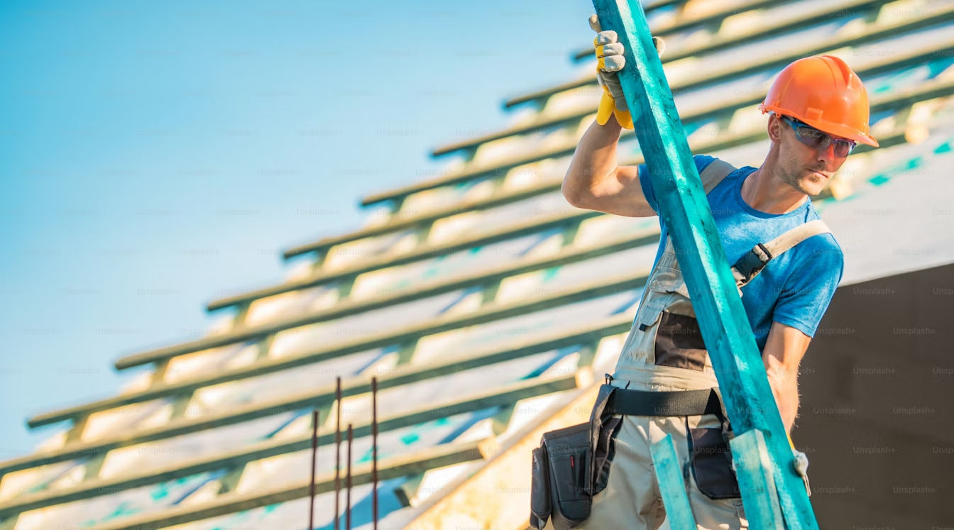 A construction worker repairing a roof on a bright, sunny day with blue sky.