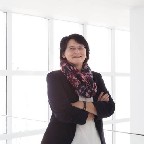 Daniela Theus lächelt mit verschränkten Armen in die Kamera