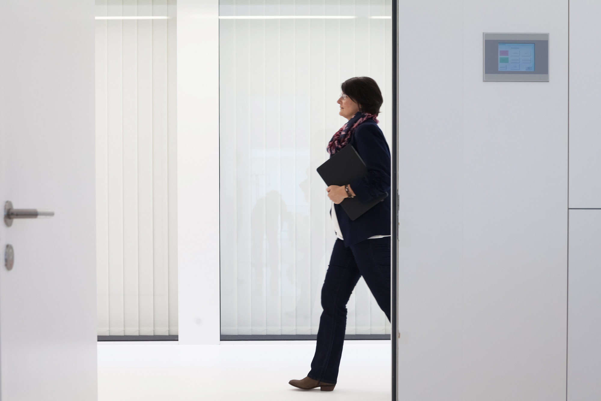Daniela Theus läuft einen Gang entlang mit einer Mappe in der Hand
