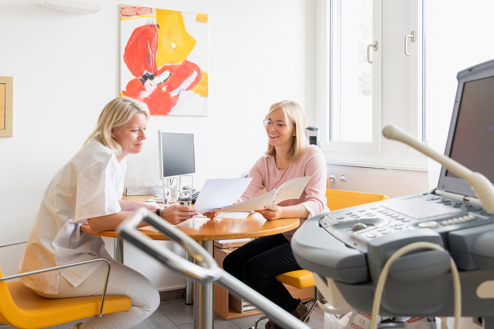 Linda Meier sitzt an einem Tisch und bespricht sich mit einer Ärztin