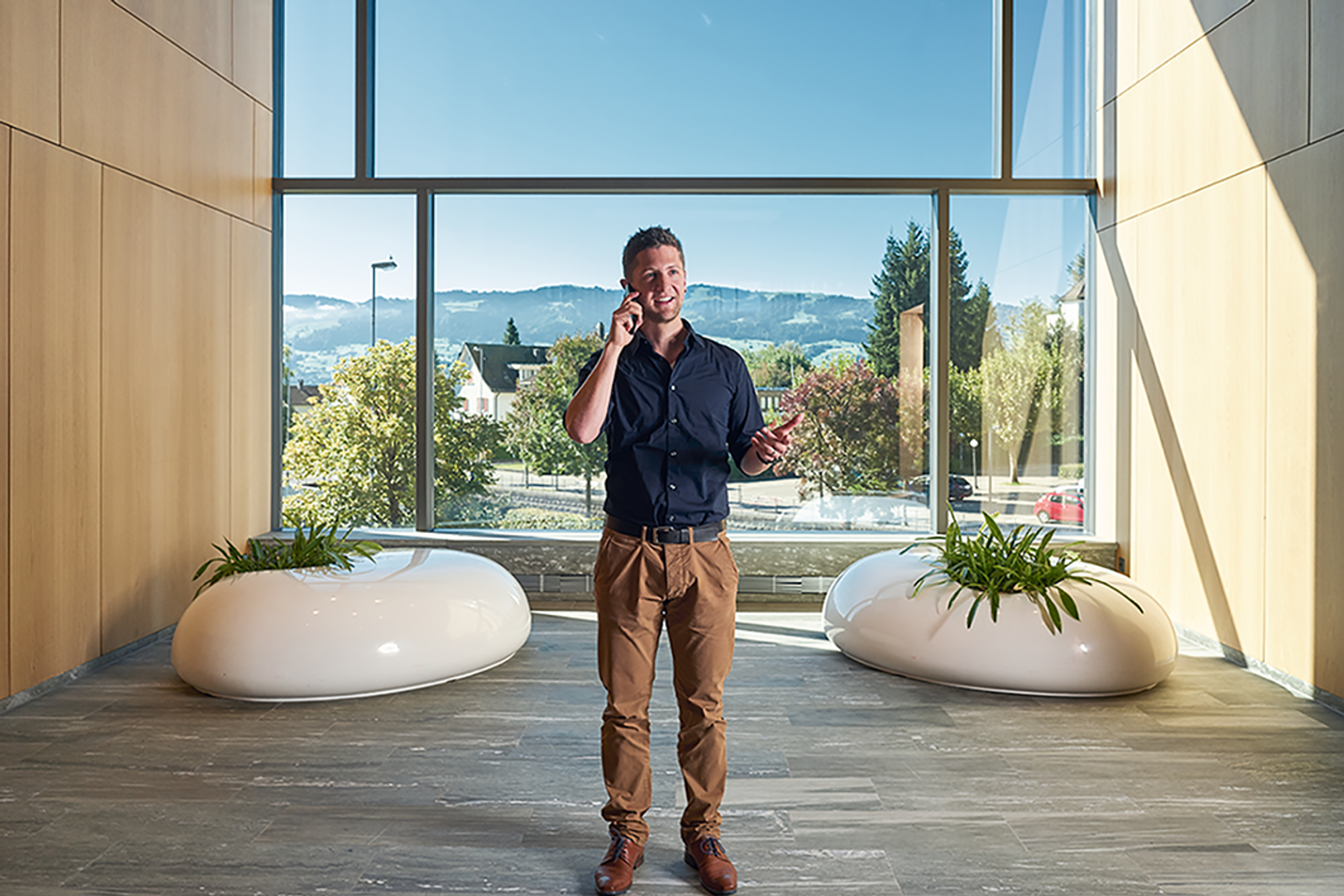 Stefan Eberhard steht in einem modernen Gebäude und telefoniert