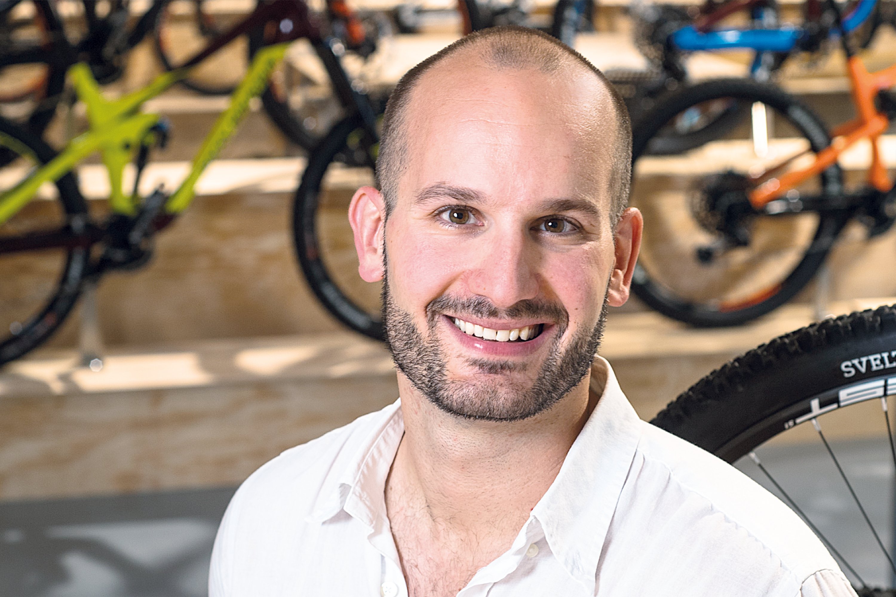 Andreas Guglielmo lächelt in die Kamera, im Hintergrund sind Fahrräder