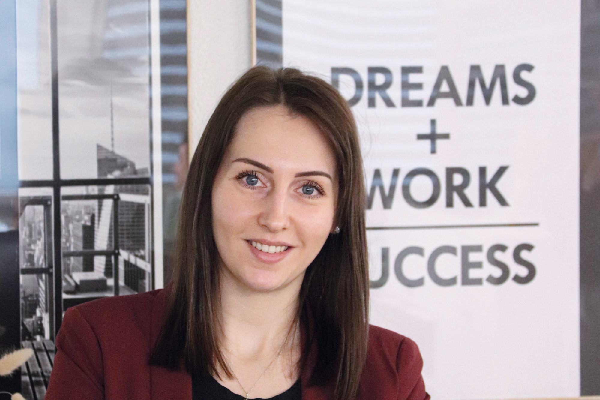 Mischella Kajtez steht vor der Kamera mit verschränken Armen und lächelt