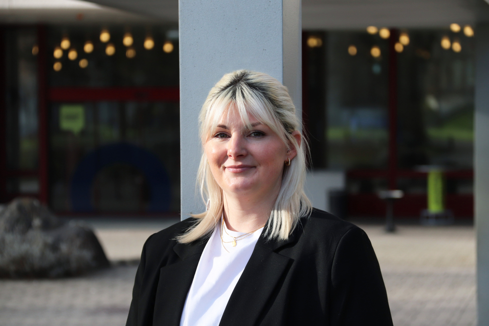 Lara Damljanovic lächelt in die Kamera und steht vor dem Gebäude der Akademie St. Gallen