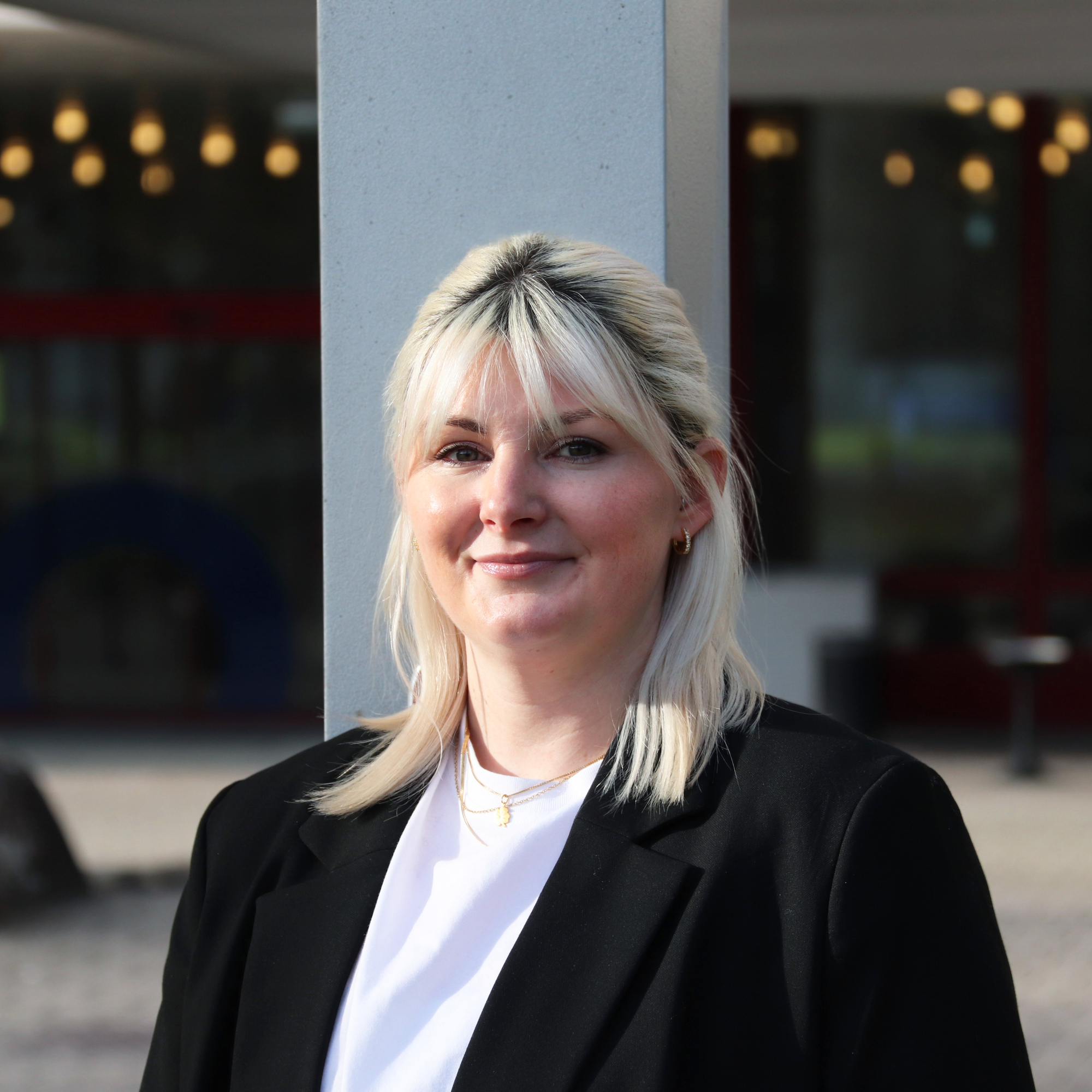 Lara Damljanovic lächelt in die Kamera und steht vor dem Gebäude der Akademie St. Gallen