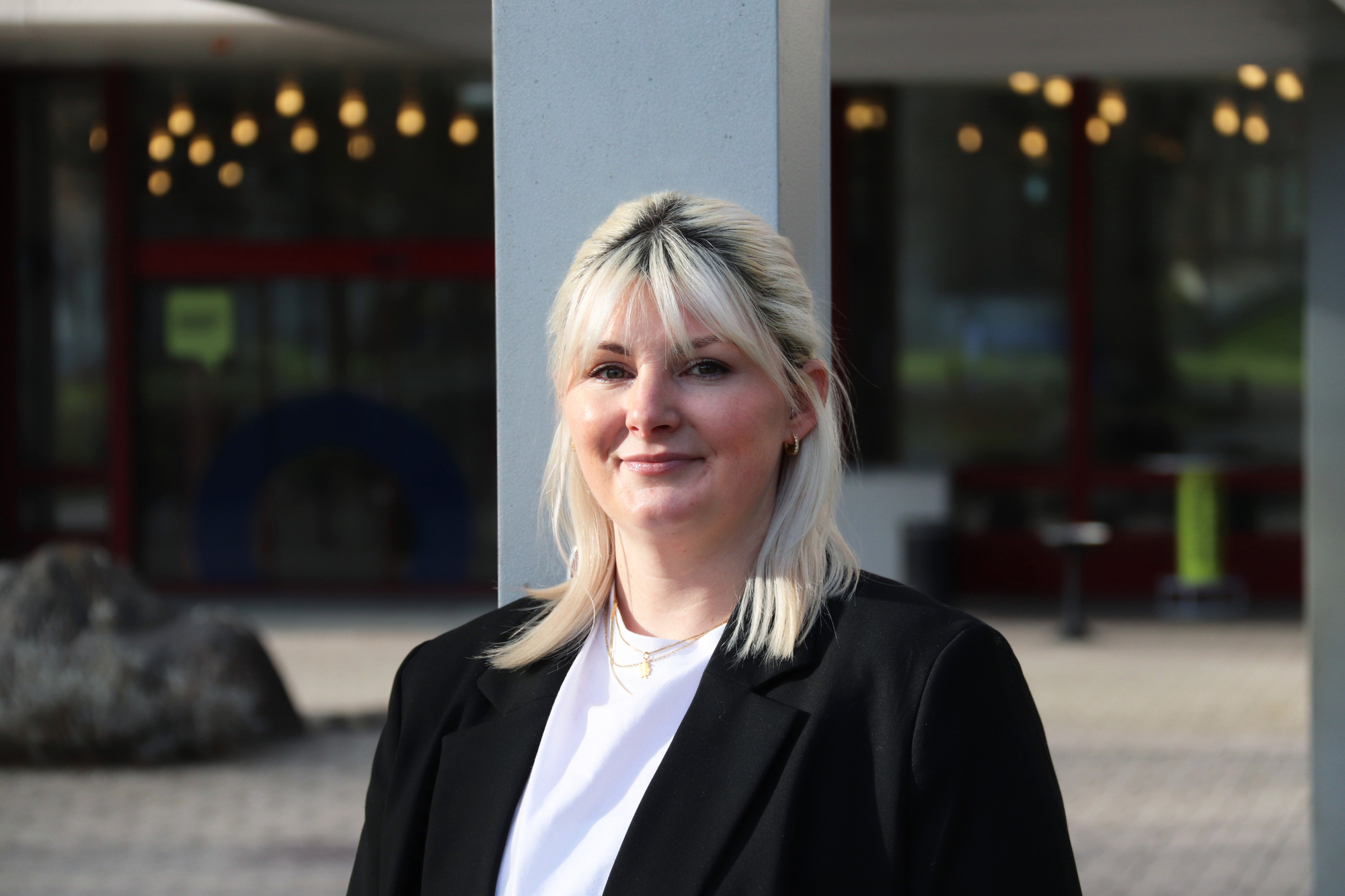 Lara Damljanovic lächelt in die Kamera und steht vor dem Gebäude der Akademie St. Gallen