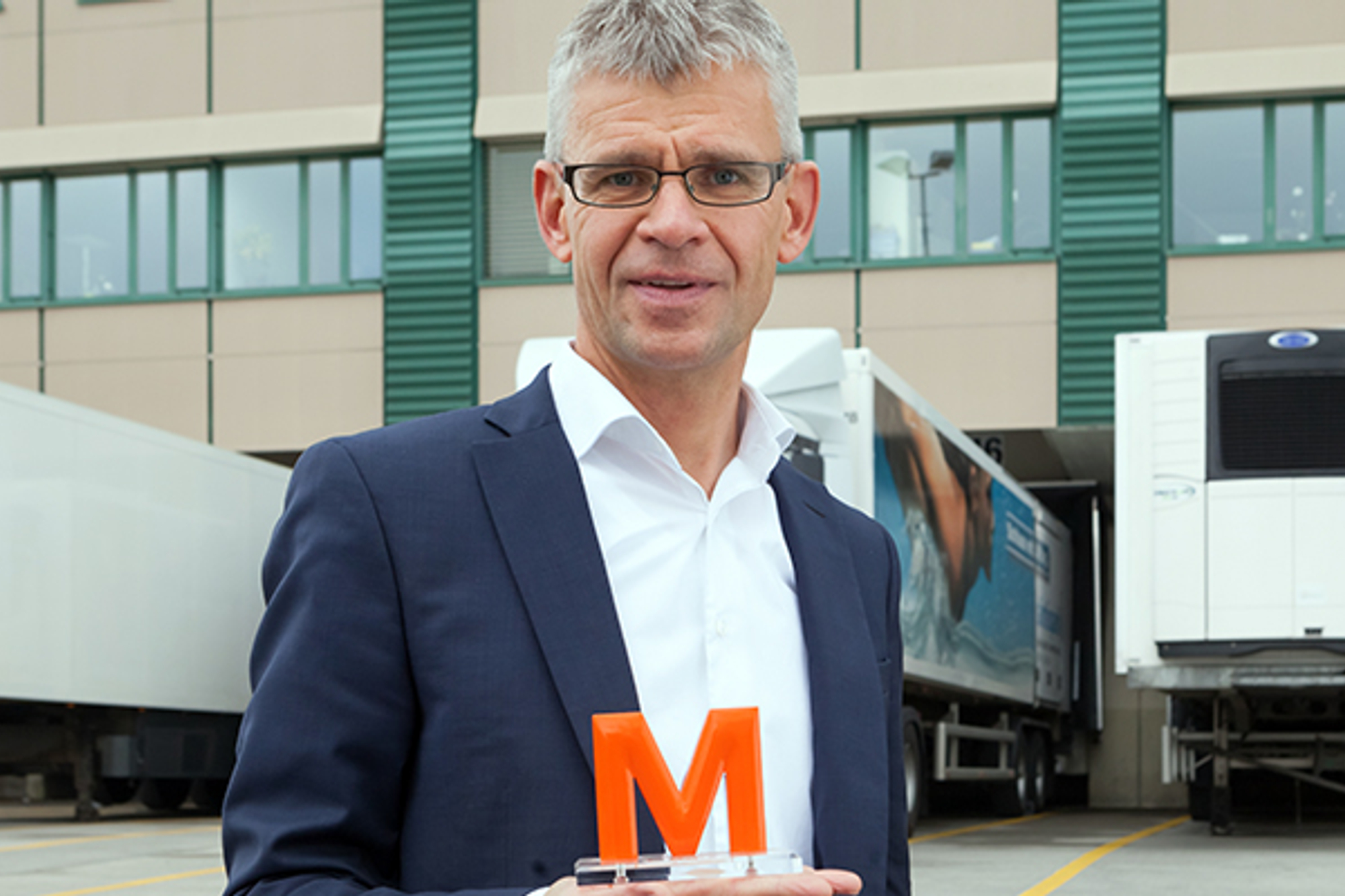 Marcel Haener hat ein oranges M in der Hand und lächelt in die Kamera