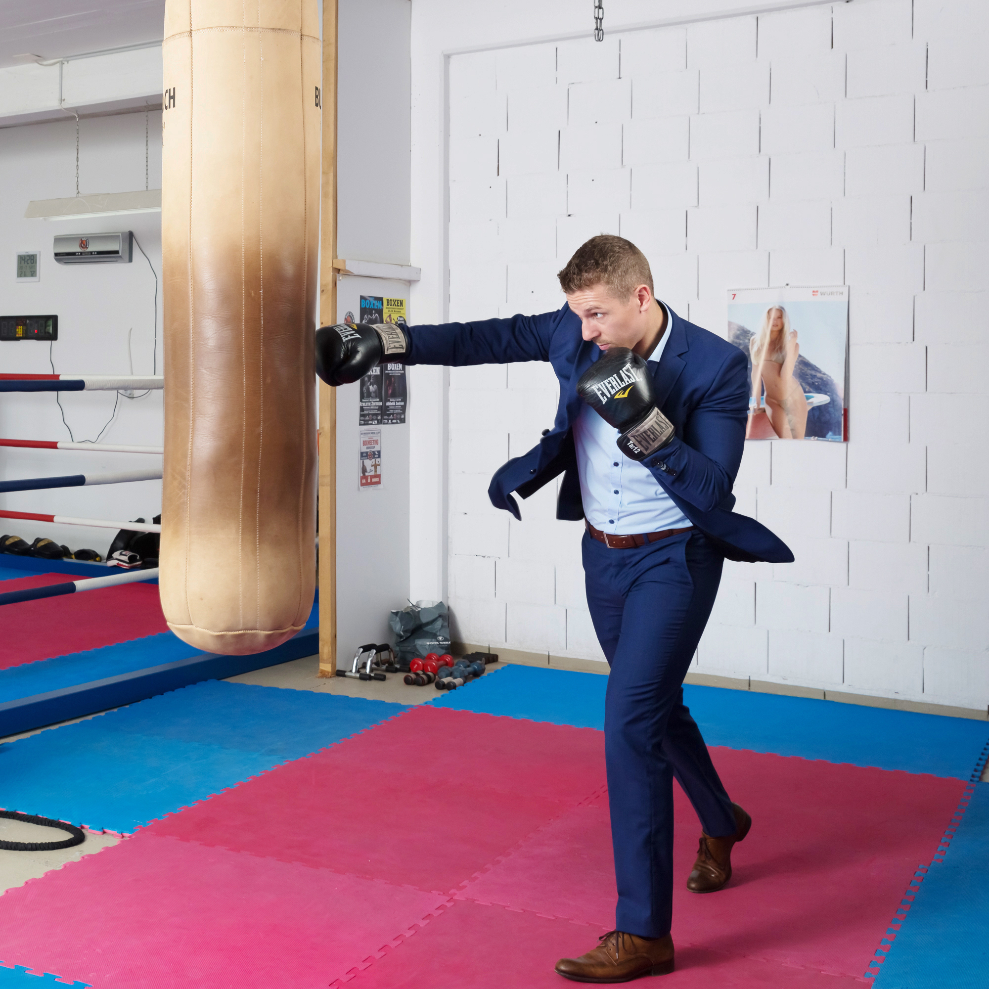 Zino Meuli boxt gegen einen Boxsack und ist im Anzug und Boxhandschuhen