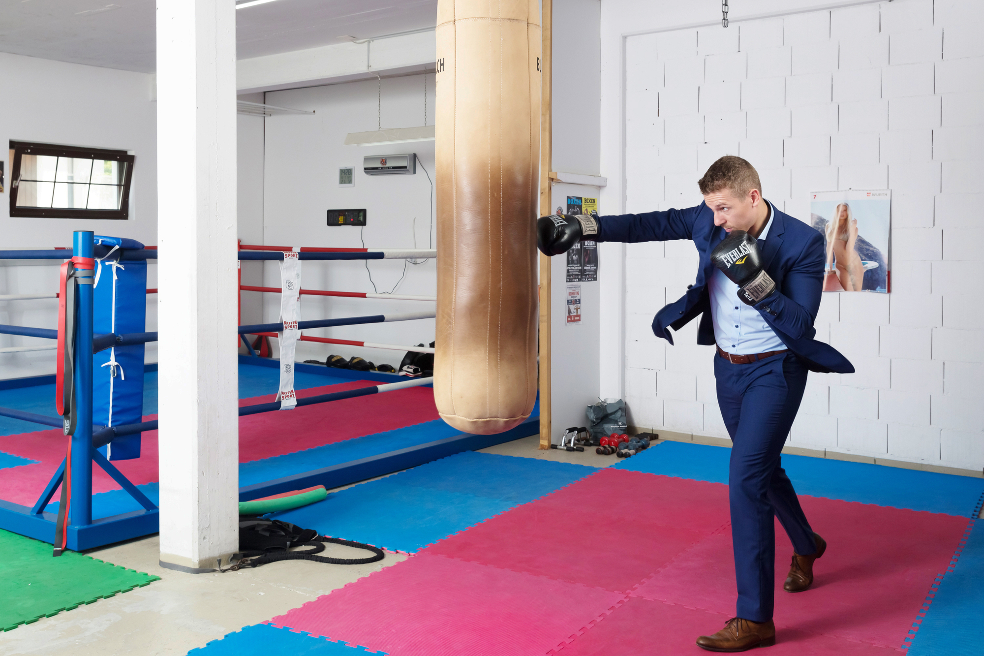Zino Meuli boxt gegen einen Boxsack und ist im Anzug und Boxhandschuhen