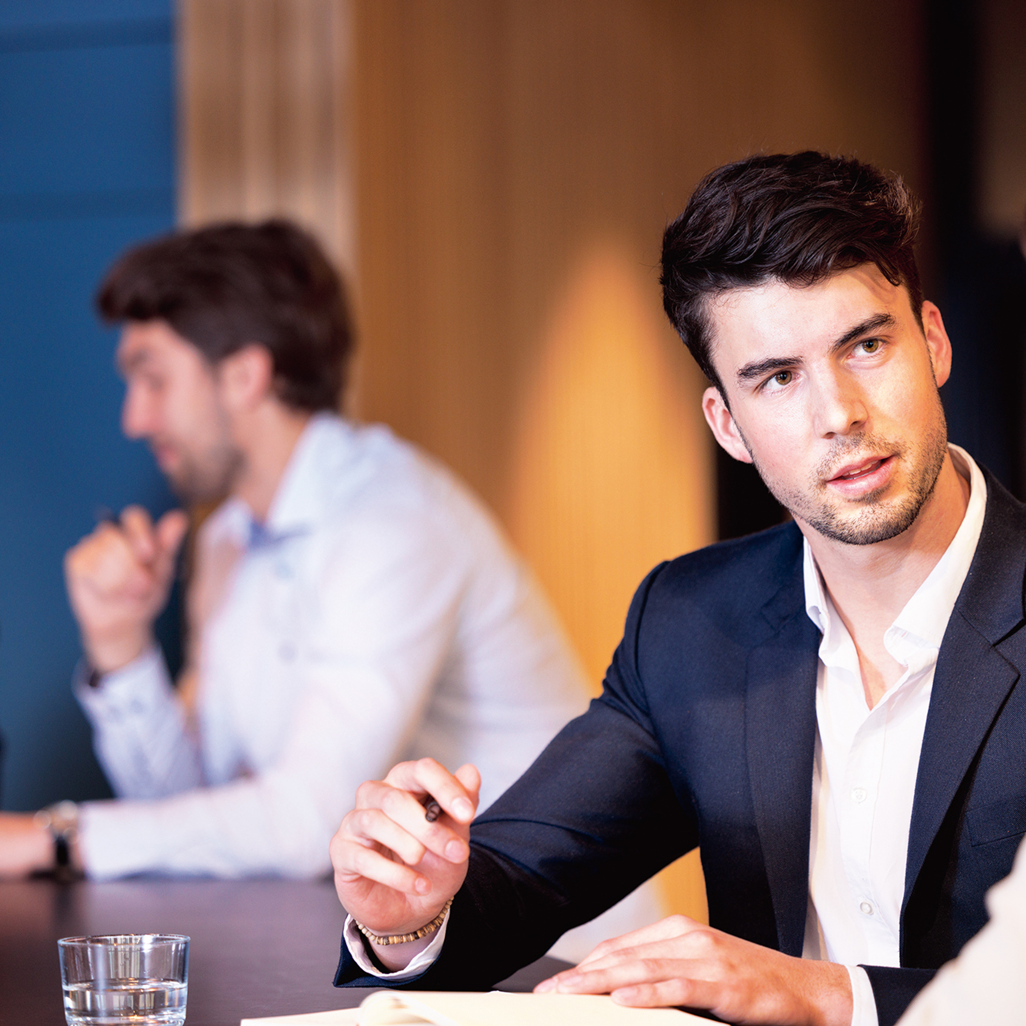 Ein Mann diskutiert mit einer Frau übers Geschäft, dabei hält er einen Kugelschreiber in der Hand.