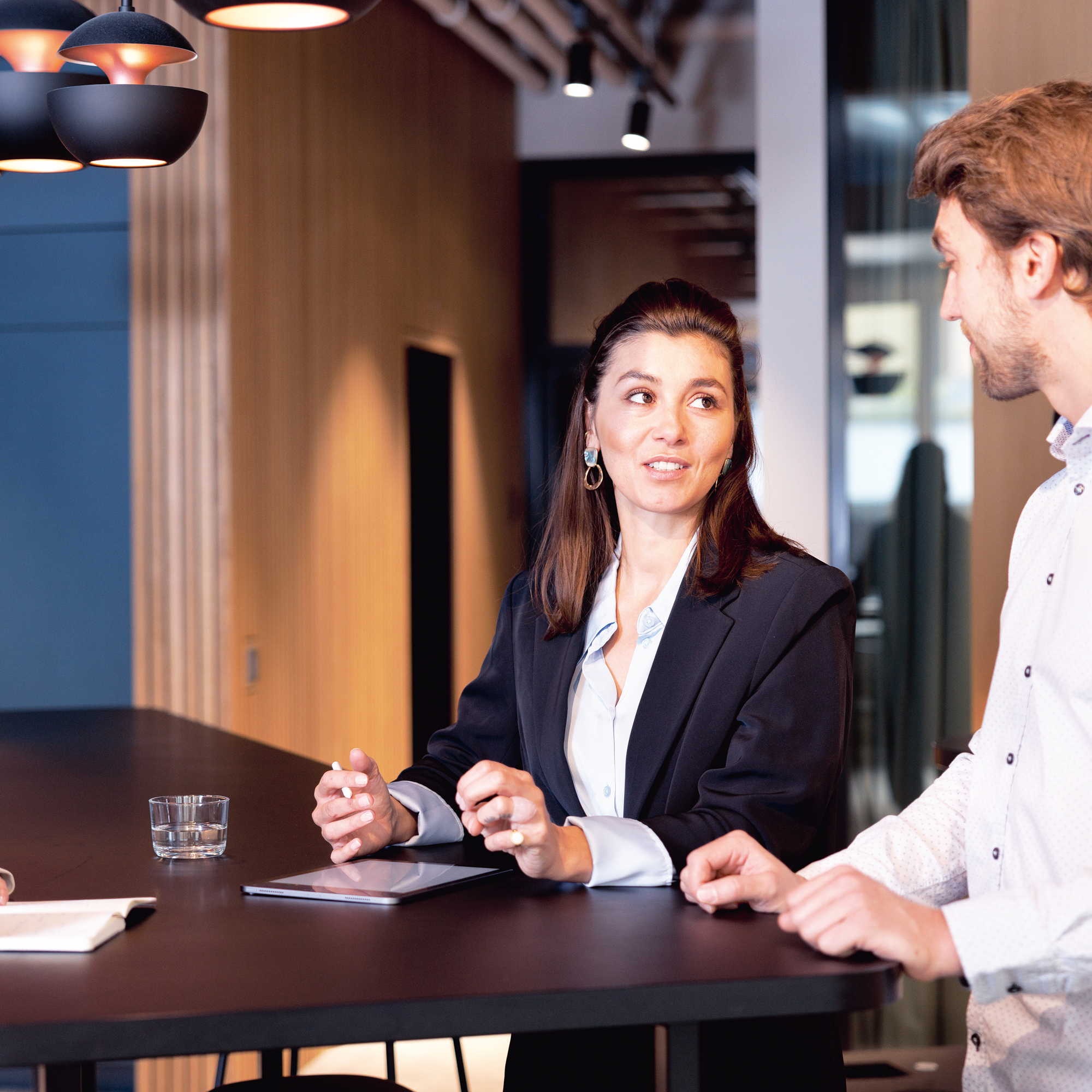 Drei Personen halten ein Meeting an einem Stehtisch.