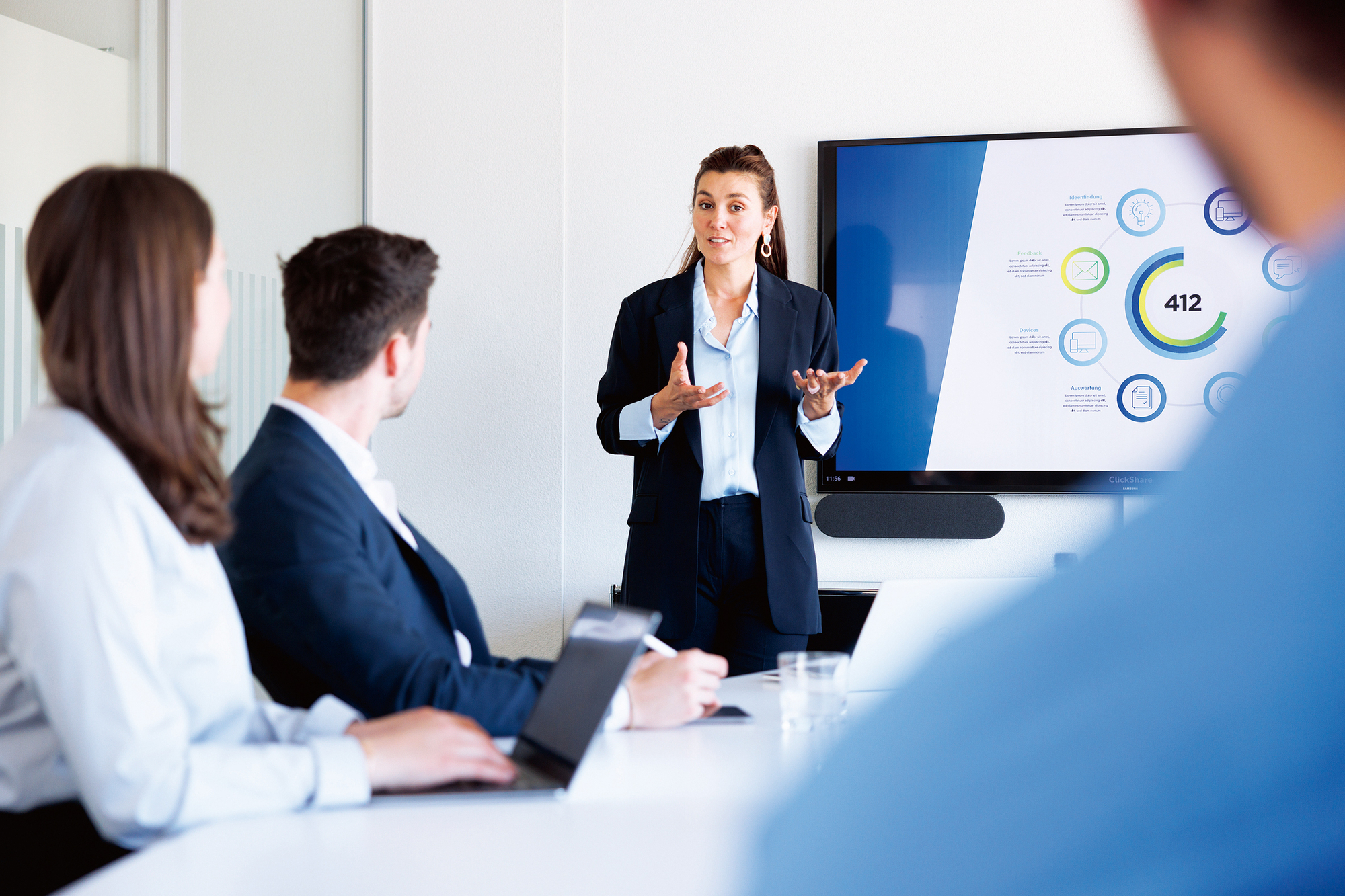 Eine Frau hält ein Meeting vor 3 anderen Personen.