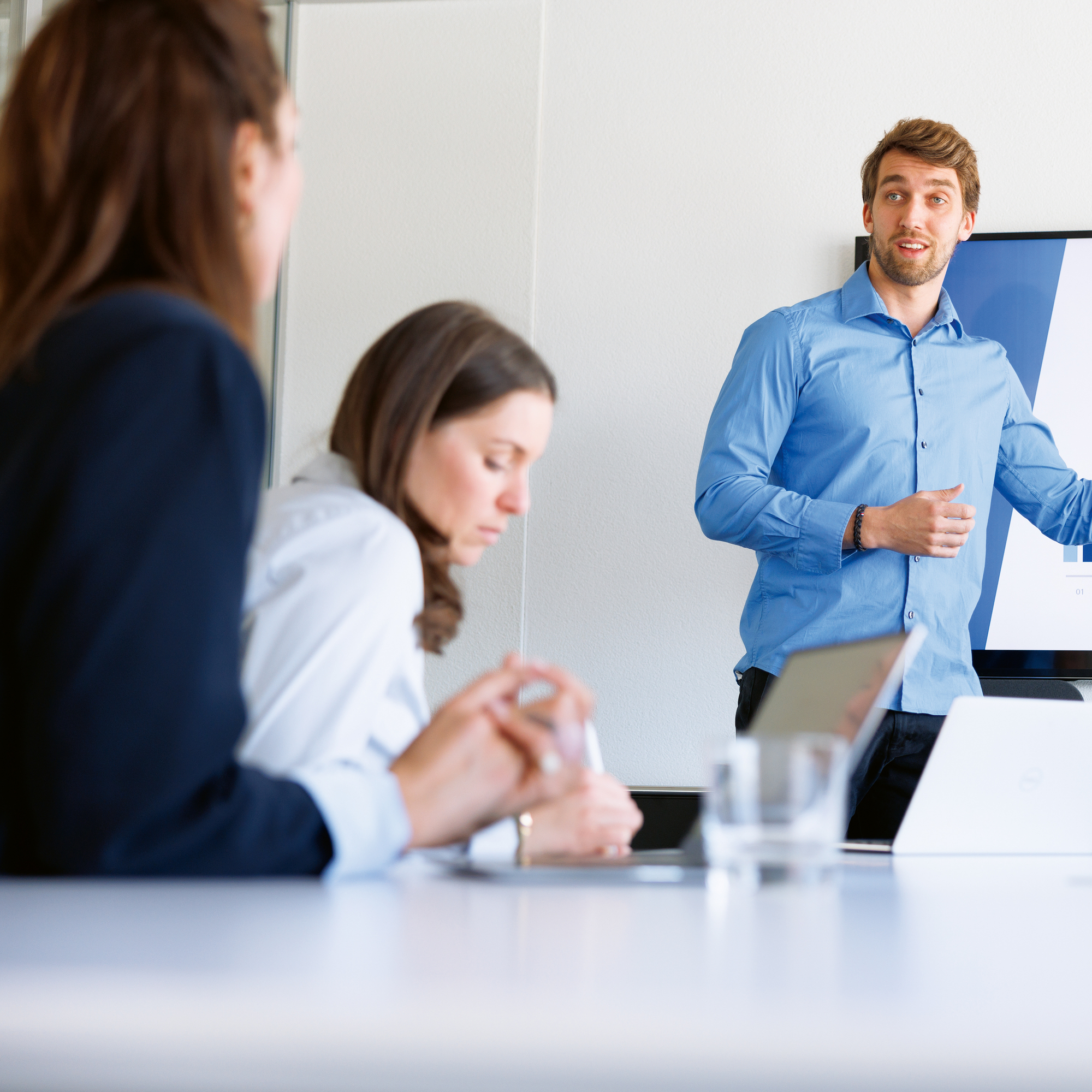 Ein Mann Präsentiert in einem Meeting die neusten Unternehmenszahlen auf einem Bildschirm