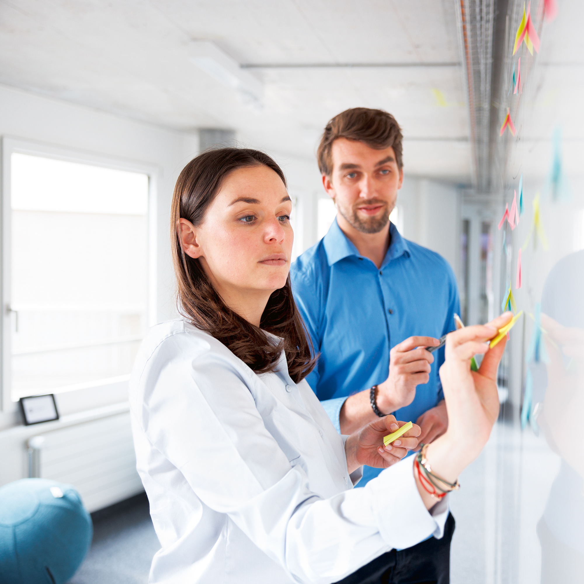 Eine Frau in weissen Hemd hält einen Workshop an einem Whiteboard, zusammen mit einem Mann in einem blauen Hemd 