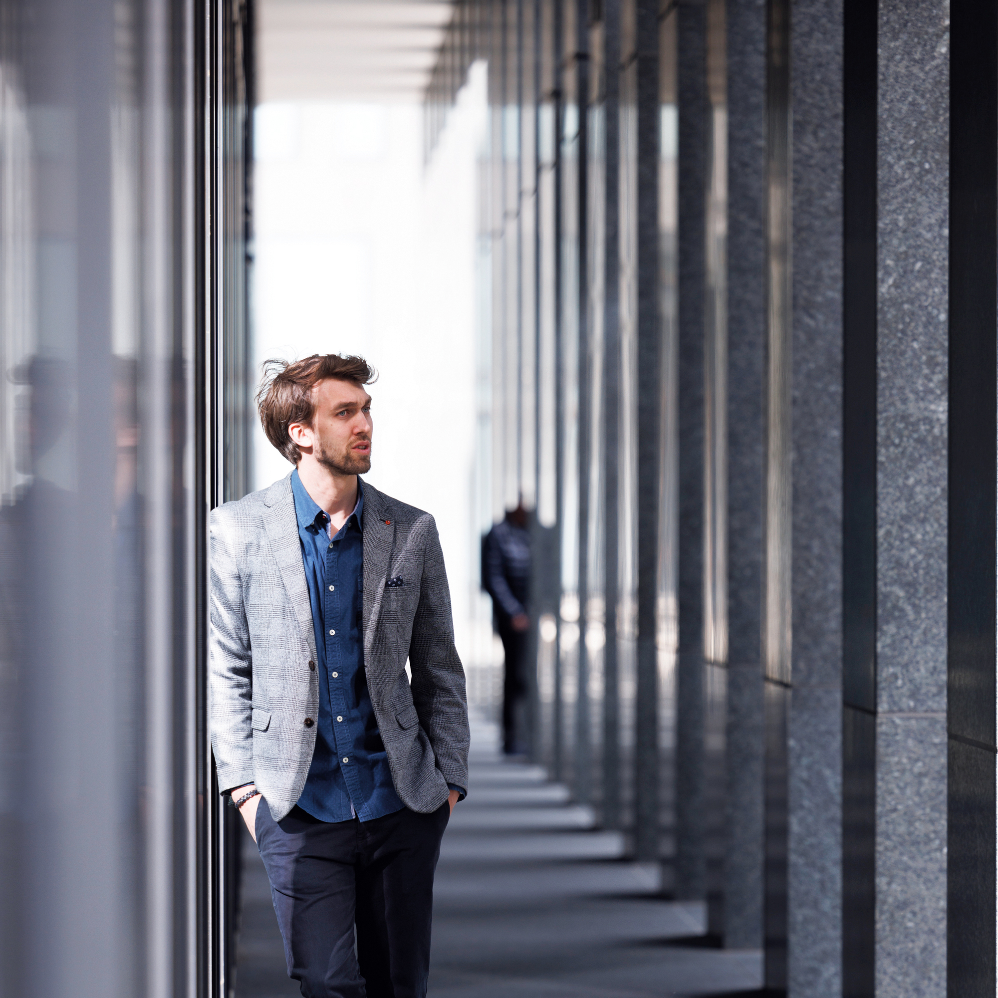 Ein Geschäftsmann lehnt an die Wand eines Bürokomplexes.