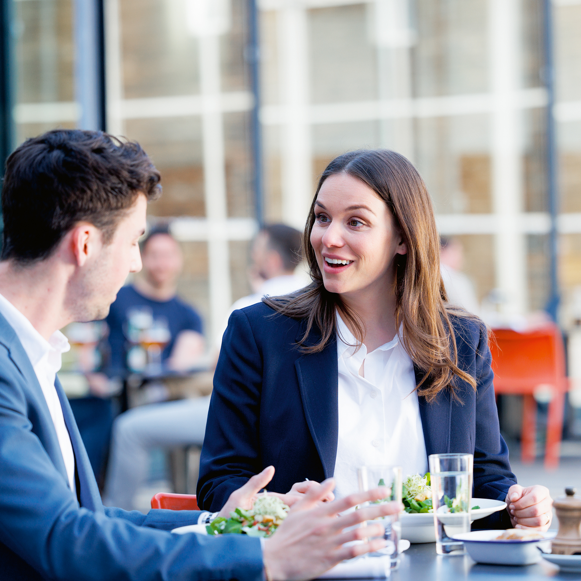 Ein Mann und eine Frau an einem Tisch diskutieren und essen dabei einen Salat.
