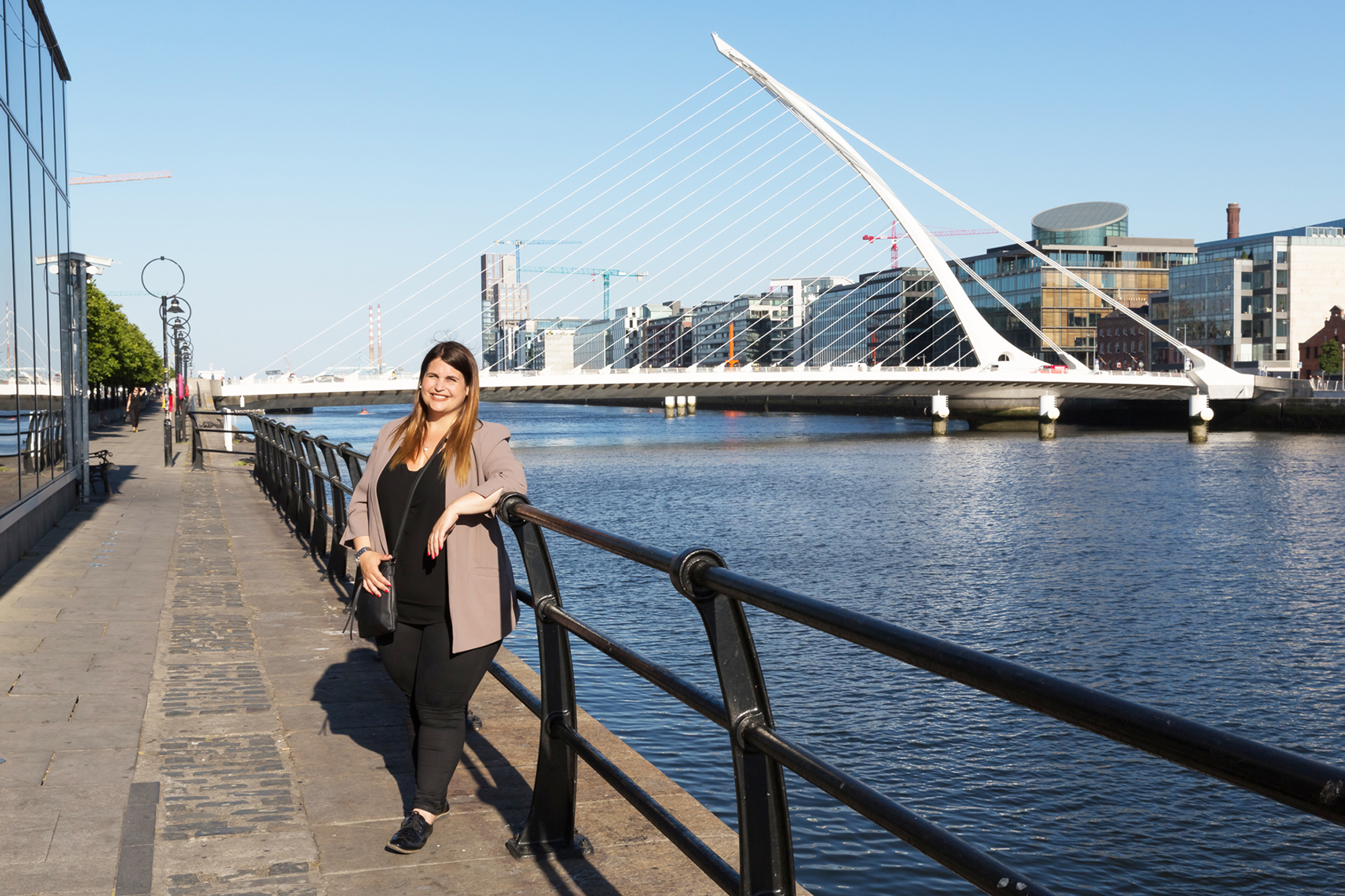 Ramona Wick steht in Dublin an einem Fluss und lehnt sich ans Geländer