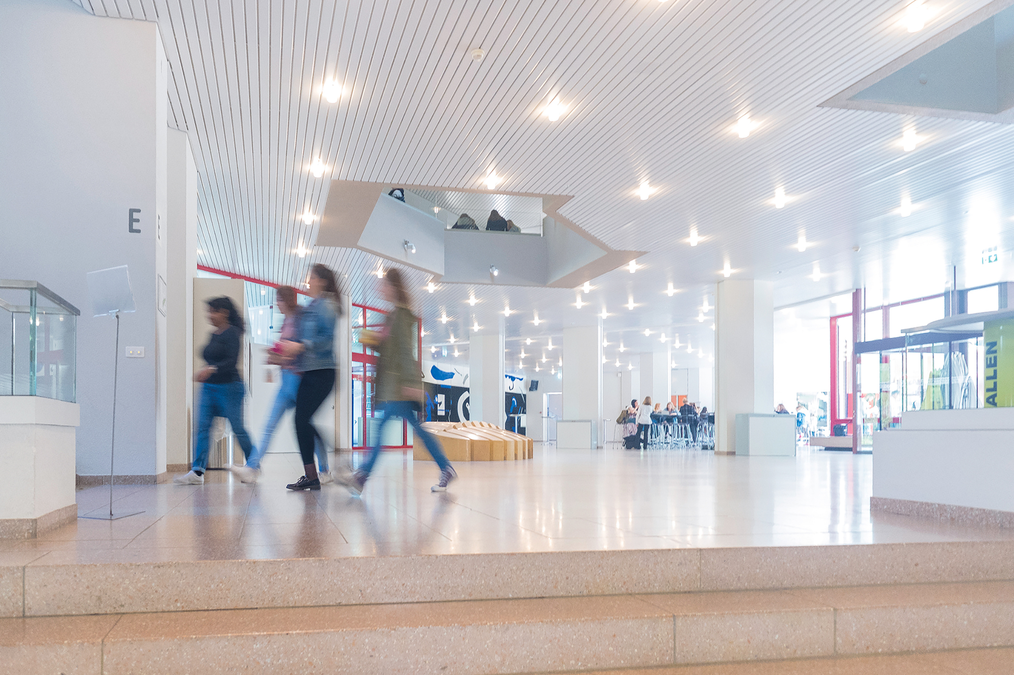 Eine Gruppe Studentinnen läuft durch die hell beleuchtete Lobby der Akademie St. Galeln