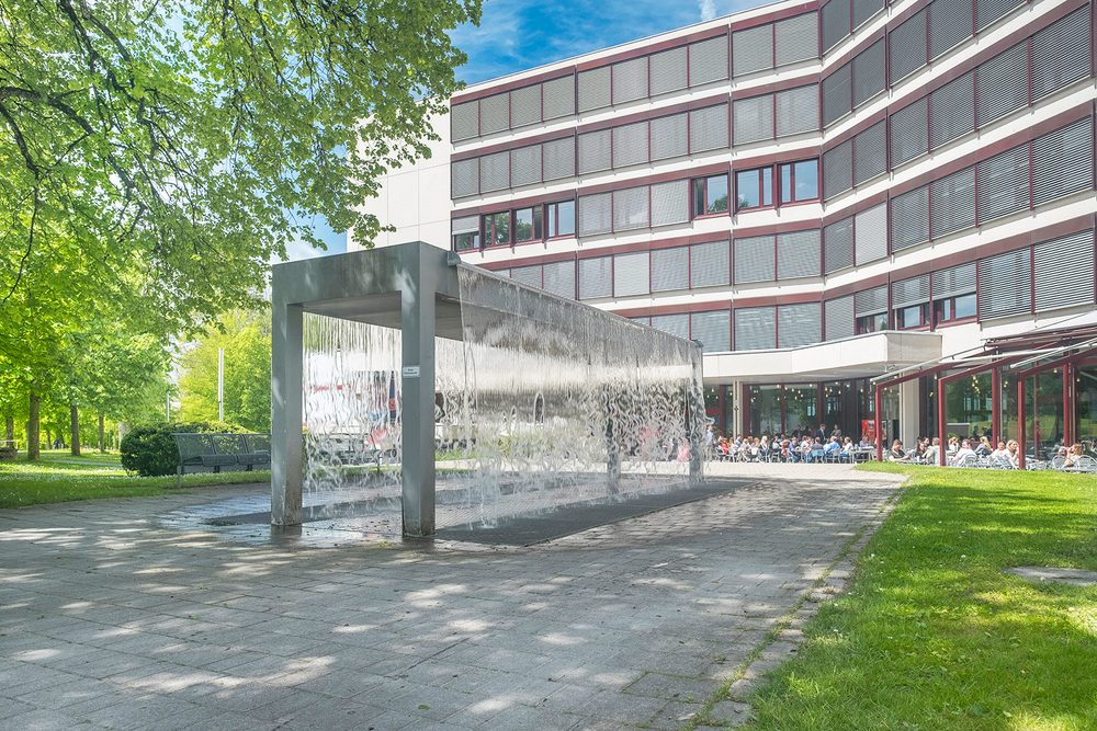 Die Aussenansicht der Akademie St. Gallen mit Brunnen, Gebäude und Grünflächen