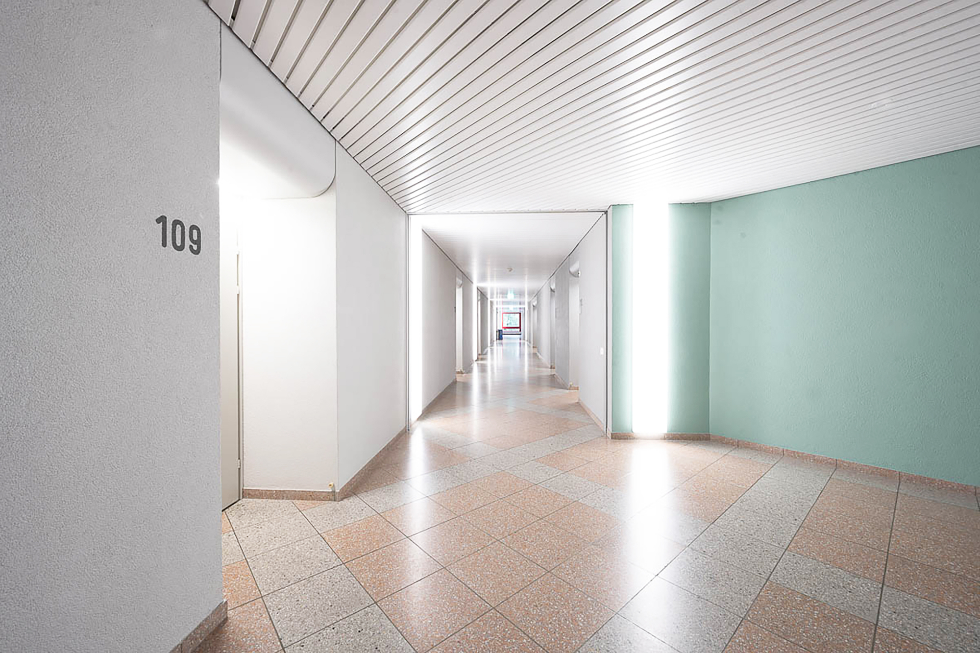 Die Hell beleuchtete Gänge der Akademie mit den Weissen und Blauen Wänden