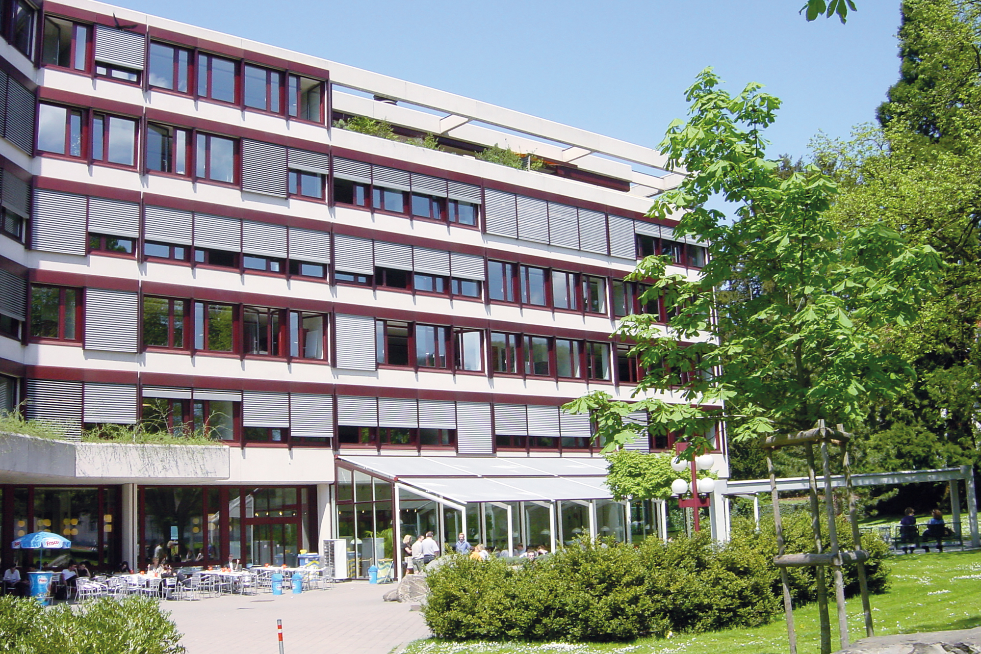 Die Aussenansicht der Akademie St. Gallen mit viel Grünflächen und dem Gebäude