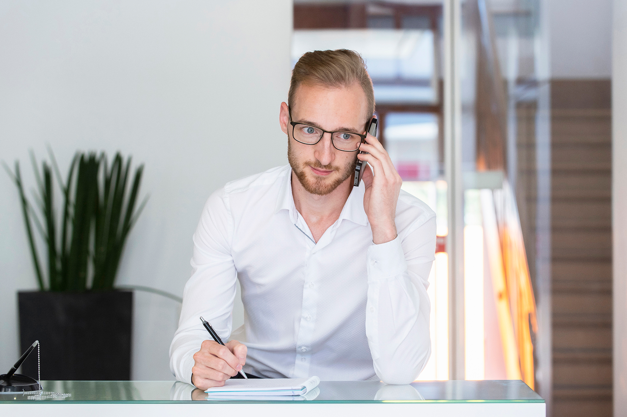 Steve Ackermann sitzt am Schreibtisch und telefoniert auf seinem Handy