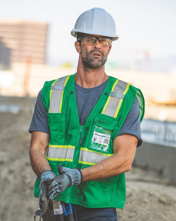 Workers wearing custom hi-vis safety vests on a job site