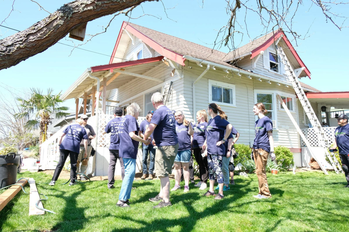 Rebuilding Together volunteers gathered on the lawn outside a house mid-repair.